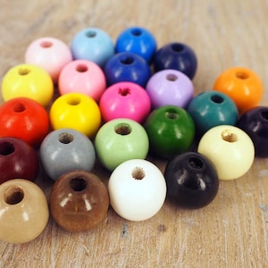 May include: A collection of 20 wooden beads in various colours, including red, blue, green, yellow, pink, purple, orange, brown, white, and grey. The beads are all round and have a hole in the centre.