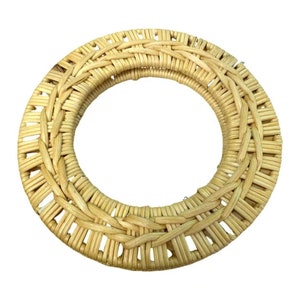 May include: A round, woven wicker coaster in a natural beige colour. The coaster is made of thin, woven strips of wicker and has a circular shape.