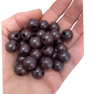 May include: A pile of dark brown wooden beads with holes in the centre. The beads are smooth and glossy.
