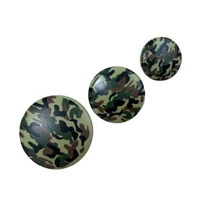 May include: Three round buttons with a camouflage pattern in shades of green, brown, and black.