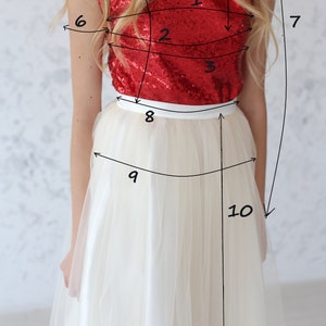 May include: A woman wearing a red sequined top and a white tulle skirt. The top has a scoop neck and sleeveless design. The skirt is full and flowing. The image is labeled with numbers 1 through 10, indicating different measurements.