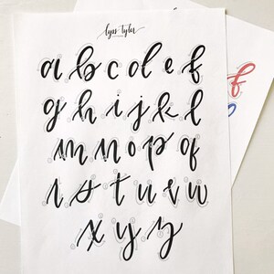 May include: A white practice sheet featuring the lowercase alphabet in black calligraphy script. Each letter includes light gray directional arrows and numbered stroke guides to demonstrate the writing process. The text lyss tyler appears at the top.