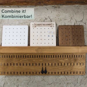 May include: A wooden earring organizer with three separate earring display boards. The boards are made of different wood types and have holes for holding earrings. The organizer has the text "Combine it! Kombinierbar!" and "KAREN'S TREASURES" on it.