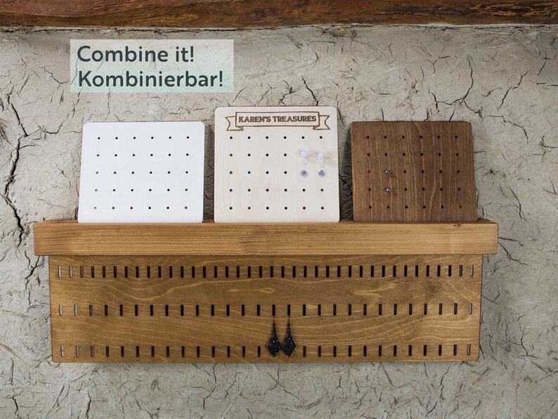 May include: A wooden earring organizer with three separate earring display boards. The boards are made of different wood types and have holes for holding earrings. The organizer has the text "Combine it! Kombinierbar!" and "KAREN'S TREASURES" on it.