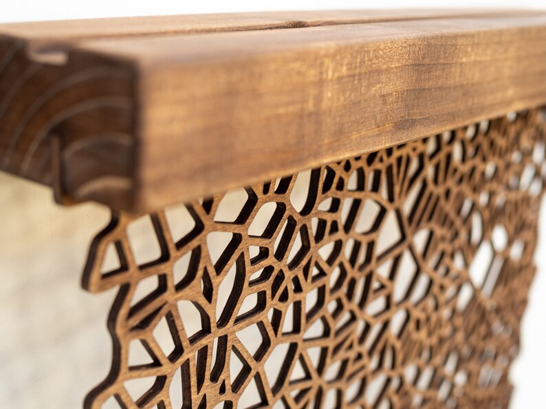 May include: A wooden wall decor with a geometric pattern cut out. The wood is a light brown color and the pattern is a dark brown color.