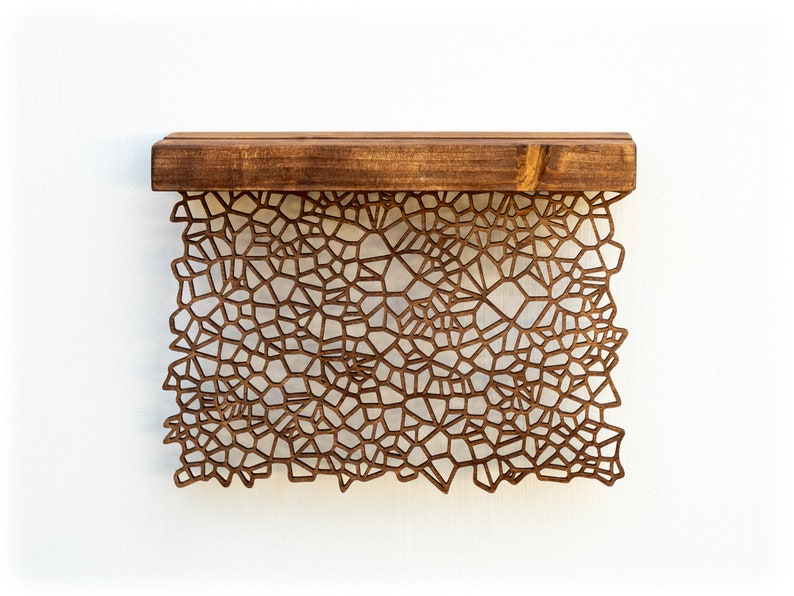 May include: A wooden shelf with a geometric pattern cut out of the front. The shelf is brown and the pattern is a light brown.