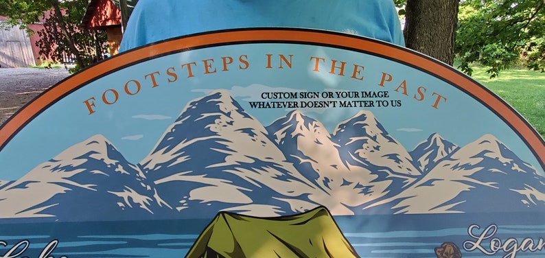 May include: A round, blue and orange sign with a mountain scene and the text "FOOTSTEPS IN THE PAST CUSTOM SIGN OR YOUR IMAGE WHATEVER DOESN'T MATTER TO US" and the name "Logan" at the bottom.