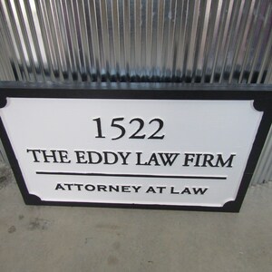Puede incluir: Un letrero en blanco y negro con el texto "1522 THE EDDY LAW FIRM ATTORNEY AT LAW".