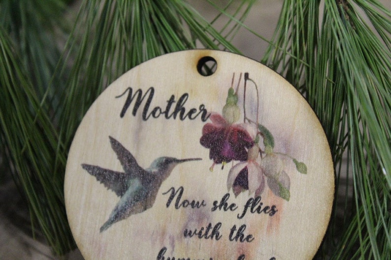May include: Wooden ornament with a hummingbird and flowers, and the text "Mother Now she flies with the hummingbirds".