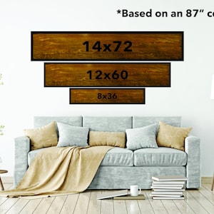 May include: Three wooden signs with black frames and white text showing different sizes of art prints, 14x72, 12x60, and 8x36. The signs are displayed on a white wall above a light gray couch with a tan throw blanket. *Based on an 87" couch*