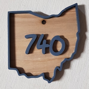 May include: A wooden cutout of the state of Ohio painted in dark blue with the number 740 in the center. The number is also painted in dark blue.