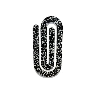 May include: A black and white decorative object with a unique U-shaped design. The object features a speckled pattern in white against a black background. The design is modern and abstract, suitable for home decor.