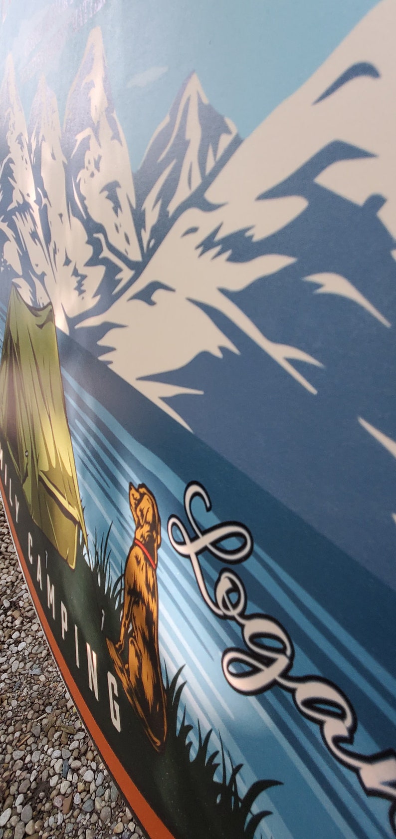 May include: A blue and white illustration of mountains and a lake with a green tent and a brown dog sitting in the grass. The text "Family Camping" is on the left side of the image and the text "Logan" is on the right side of the image.
