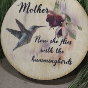 May include: A wooden ornament with a hummingbird and a flower, and the text "Mother Now she flies with the hummingbirds".