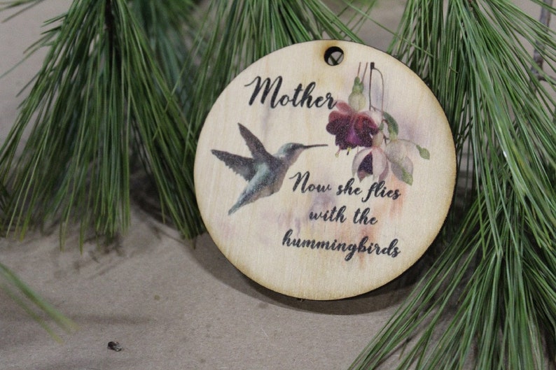 May include: A wooden ornament with a hummingbird and a flower, and the text "Mother Now she flies with the hummingbirds".