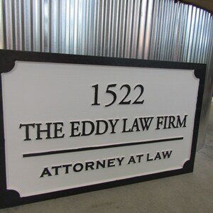 Puede incluir: Un letrero blanco con letras negras y un borde negro. El letrero dice "1522 The Eddy Law Firm Attorney at Law".