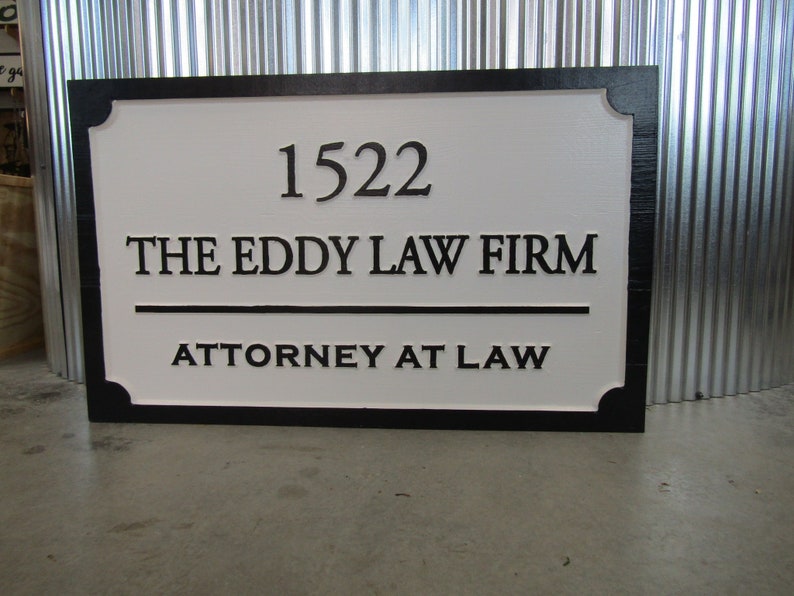 Puede incluir: Un letrero de madera blanco y negro con el texto "1522 The Eddy Law Firm Attorney at Law".
