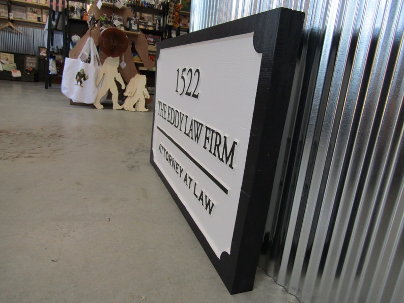 Puede incluir: Un letrero blanco y negro con marco negro. El letrero dice "1522 The Eddy Law Firm Attorney at Law".