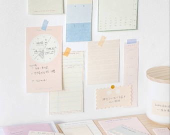 May include: A collection of colorful sticky notes with different designs and patterns. The notes are arranged on a white wall and a wooden surface. Some of the notes have handwritten text, including a calendar, a weekly planner, and a pie chart. The notes are perfect for organizing tasks, ideas, and reminders.