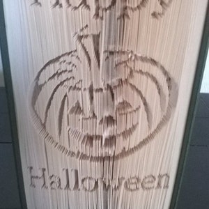 May include: A book with the words "Happy Halloween" folded into the pages to create a 3D image of a jack-o'-lantern.