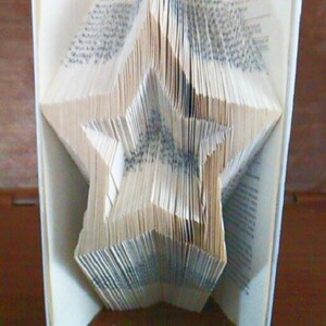 Op de afbeelding: Een boek gevouwen in de vorm van een ster. De pagina's zijn gevouwen op een manier die een driedimensionale stervorm creëert.