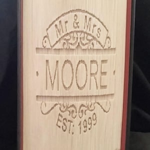 May include: A book with a custom design on the cover. The design features the text "Mr. & Mrs. MOORE EST. 1999" with a decorative flourish.