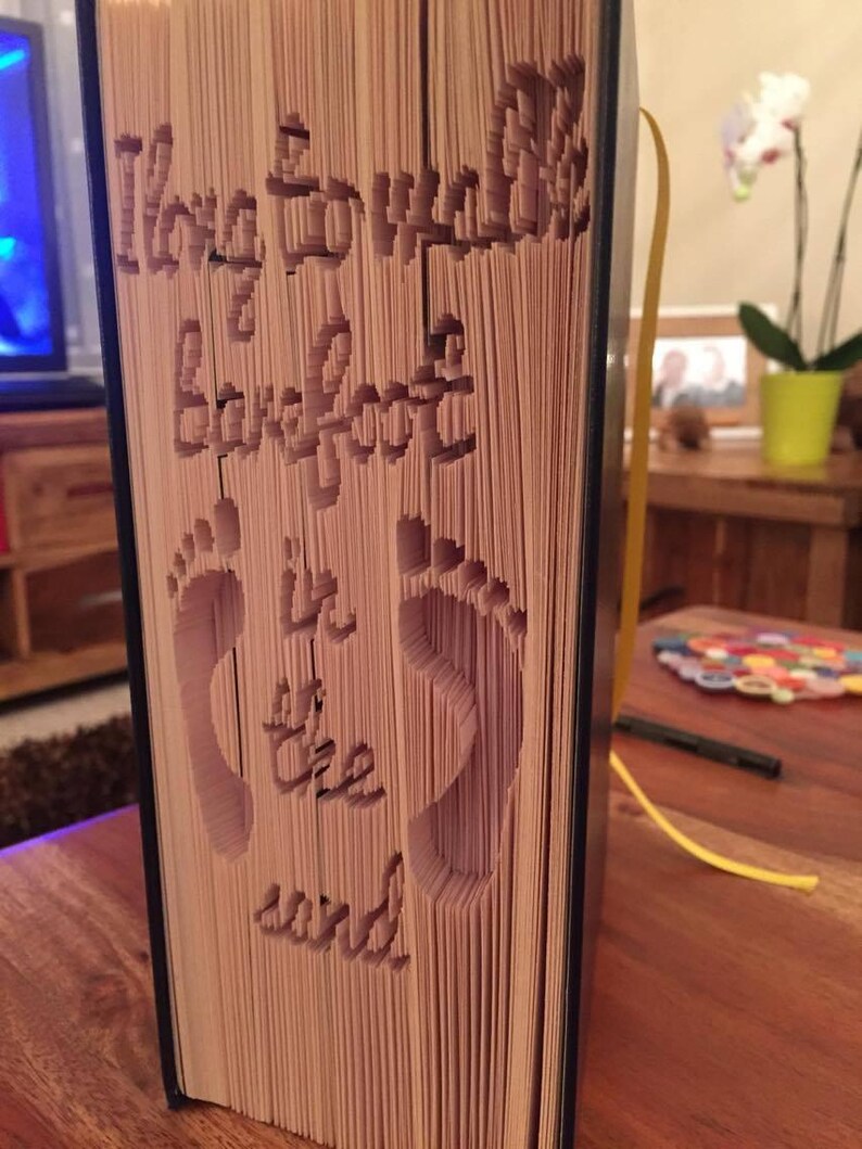 May include: A book with the words "I love to walk barefoot in the sand" cut out of the pages. The pages are folded to create a 3D effect.