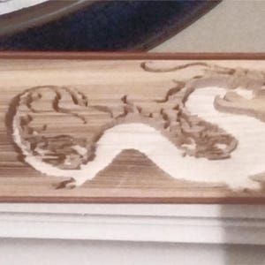 May include: A book with a dragon design carved into the spine. The dragon is made of paper and is white against the brown background of the book.