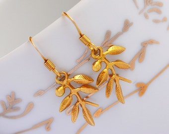 Puede incluir: Pendientes de rama de olivo dorados con un diseño delicado. Los pendientes están hechos de metal dorado y presentan una pequeña rama de olivo con hojas y bayas.