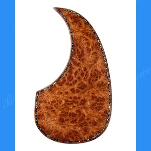 Puede incluir: Un golpeador de guitarra de madera maciza de burl, dise&ntilde;ado para un Martin D45. El golpeador tiene una forma &uacute;nica con un patr&oacute;n de vetas de madera marr&oacute;n oscuro. El borde est&aacute; incrustado con un borde decorativo. El texto "Bruce Wei Musical Instruments Workshop" est&aacute; en la parte superior.