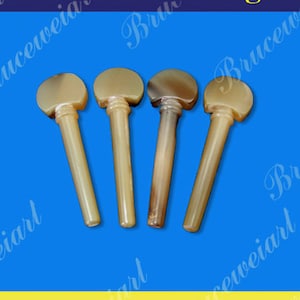 以下が含まれることがあります： 茶色と白の角製のビオラペグが4つ。ペグは天然素材で作られており、滑らかで磨かれた仕上げになっています。ペグは一列に並んでおり、各ペグの上部は視聴者の方を向いています。ペグには「35」という番号が付けられています。