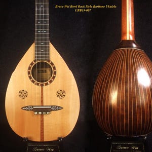 May include: A light-colored baritone ukulele with a rounded body and a dark brown back. The front features a sound hole with a decorative border and two ornate sound holes. The text "Bruce Wei Bowl Back Style Baritone Ukulele UBB19-007" is visible.