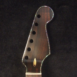 May include: Close-up of an electric guitar neck. The dark wood neck has a decorative edge and inlay around the headstock. The text "Bruce Wei Electric Guitar Neck GN-2106" is at the top.