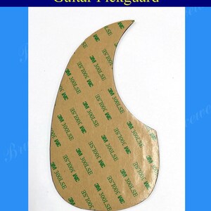 Puede incluir: Un golpeador de guitarra marr&oacute;n con forma de media luna y respaldo adhesivo. El respaldo adhesivo est&aacute; cubierto con cinta adhesiva verde 3M 300LSE.