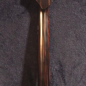 May include: A guitar neck with a dark brown and reddish-brown wood grain pattern. The headstock has six tuning peg holes. The text "Bruce Wei Electric Guitar Neck GN-2113" is visible.