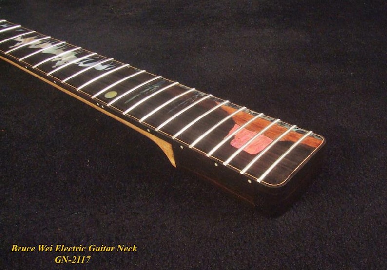 May include: Close-up of an electric guitar neck with white frets on a dark wood fretboard. The neck has a natural wood finish and a decorative inlay. The text "Bruce Wei Electric Guitar Neck GN-2117" is visible.