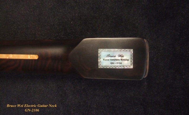 May include: Close-up of a dark brown electric guitar neck with a light-colored inlay. The headstock features a label with the text "Bruce Wei Musical Instruments Workshop GN-2106."