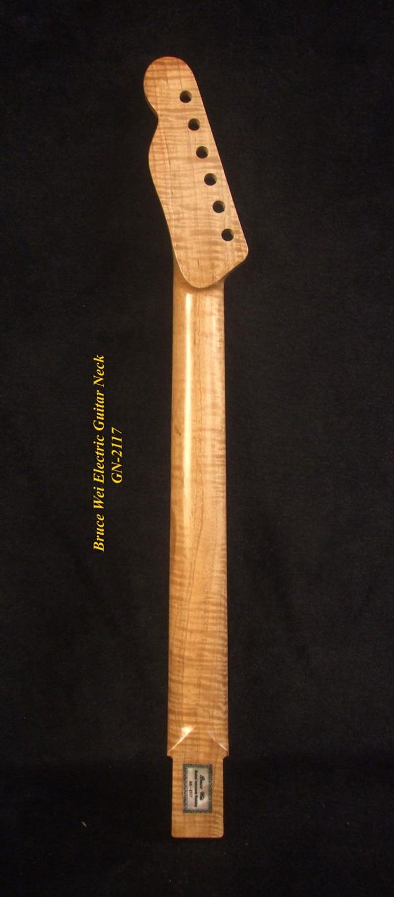 May include: A light-colored, unfinished electric guitar neck with a headstock featuring six tuning peg holes. The neck has a smooth, glossy finish and the text "Bruce Wei Electric Guitar Neck GW-2117".