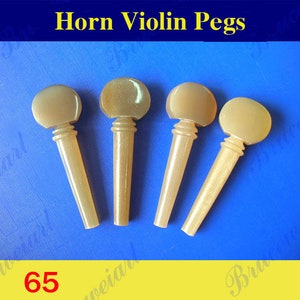 以下が含まれることがあります： 角製のベージュのバイオリンペグが4つ。ペグは青い表面に一列に並んでいます。画像の上部には「Horn Violin Pegs」というテキストが、下部には「65」という数字があります。