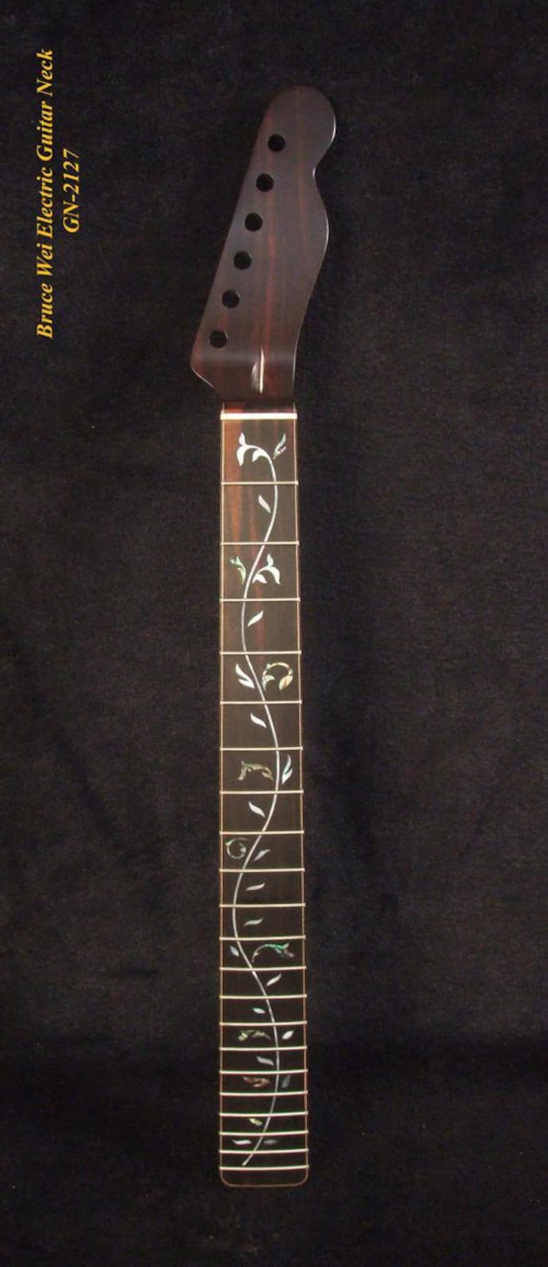 May include: A dark brown electric guitar neck featuring a headstock with six tuning peg holes and a fretboard inlaid with a continuous mother-of-pearl vine pattern. The text "Bruce Wei Electric Guitar Neck GN-2127" is printed on the left side.