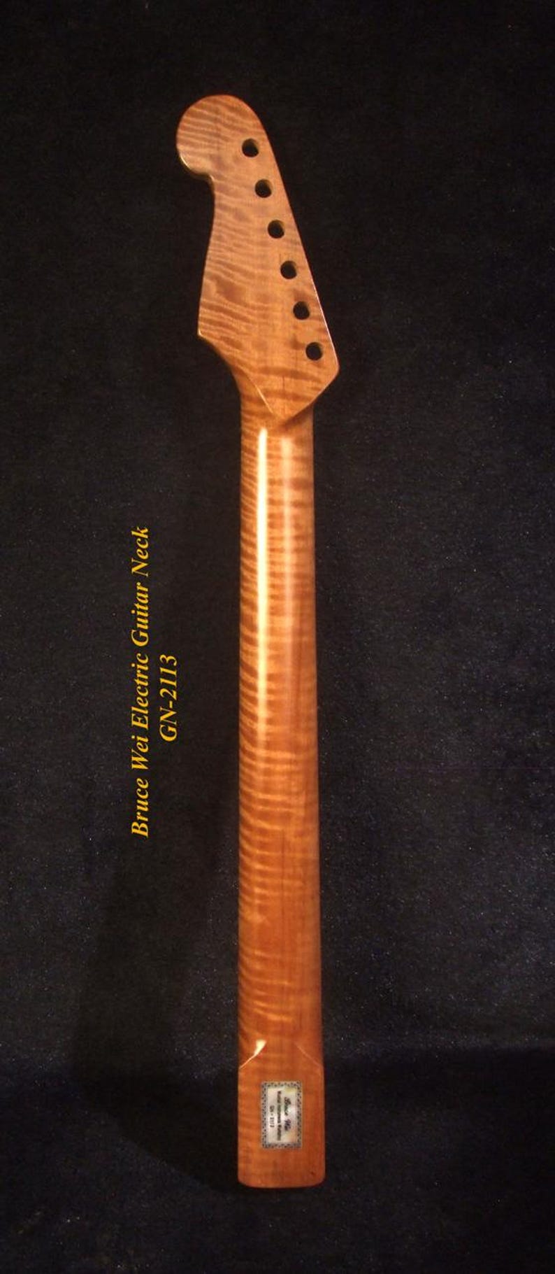 Op de afbeelding: Houten elektrische gitaarhals met een gevlamd esdoornnerfpatroon. De hals heeft een kop met zes stemgaten en een gladde, gepolijste afwerking. De tekst "Bruce Wei Electric Guitar Neck GN-2113" is zichtbaar.