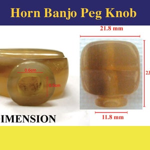 Pode incluir: Um close-up de um botão de pino de banjo de chifre marrom. O botão tem 21,8 mm de largura, 23,4 mm de altura e 11,8 mm de espessura. O botão tem um furo no centro com 0,6 cm de diâmetro.