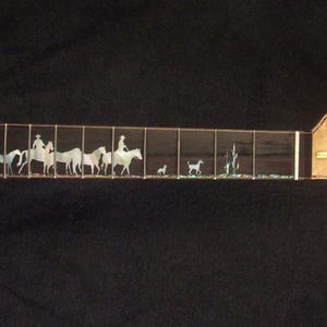 May include: Electric guitar neck with a detailed inlay depicting a Western scene. The fretboard features a red cowboy hat, riders on horseback, and desert plants. The headstock is a light wood color with tuning peg holes. The text "Bruce Wei Electric Guitar Neck GN-2117" is at the bottom.