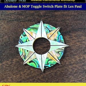 May include: Abalone and MOP toggle switch plate for a Les Paul guitar. The plate is a star shape with a green, blue, and gold iridescent finish. The text "SP6" is visible in the lower left corner of the image.
