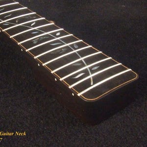 May include: A dark wood electric guitar neck featuring a fretboard with silver-toned metal frets and an intricate vine-like inlay pattern made of iridescent shell material. The text Bruce Wei Electric Guitar Neck GN-2127 is printed in yellow.