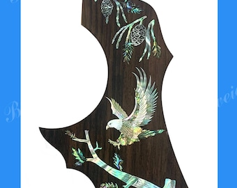May include: A guitar pickguard with a dark wood grain finish, featuring an inlaid design of an eagle, branches, and pinecones. The pickguard is designed to fit an Epiphone FT-120 Masterbilt Excellente guitar.