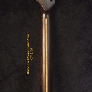May include: Close-up of an electric guitar neck with a dark wood grain finish. The headstock has six tuning peg holes. The text "Bruce Wei Electric Guitar Neck GN-2106" is printed on the neck.