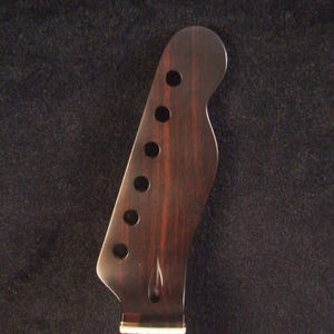 May include: A dark brown wooden electric guitar neck headstock with six circular tuning peg holes. The text Bruce Wei Electric Guitar Neck GN-2127 is visible at the top. The fretboard features a white floral inlay pattern near the nut.