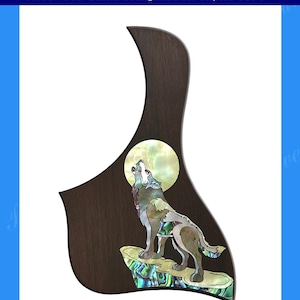 May include: A rosewood guitar pickguard with a wolf howling at the moon inlay. The inlay is made of mother of pearl and features a wolf howling at the moon. The pickguard is designed to fit a Taylor 517e guitar.