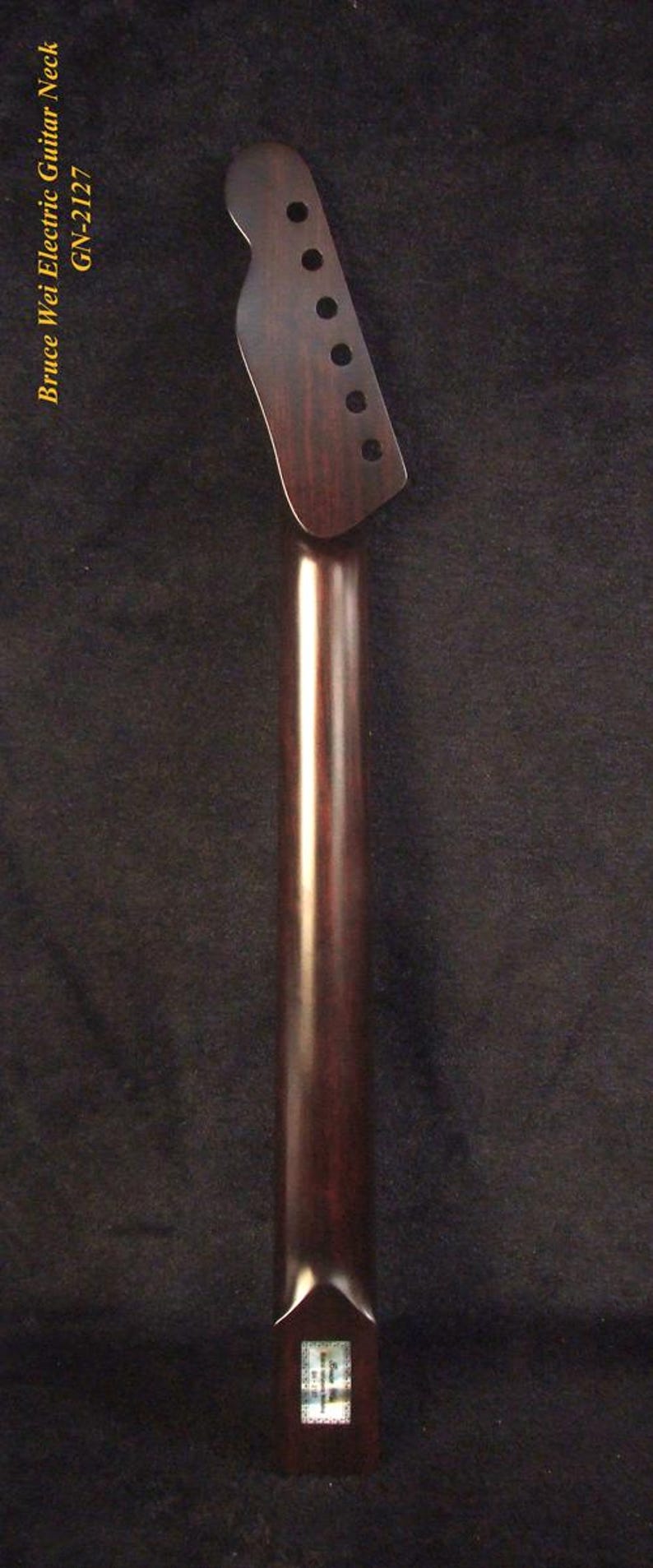 May include: A dark brown wooden electric guitar neck with a headstock featuring six tuner holes. The text Bruce Wei Electric Guitar Neck GN-2127 is printed vertically along the left side. A small rectangular label is visible at the base.